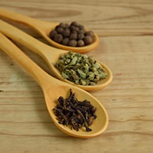 Three wooden spoons containing different herbs and spices, which could represent natural biofilm disruptor ingredients used in alternative medicine.