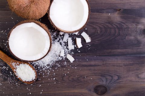 Image of coconuts and coconut flakes on a wooden surface, showcasing raw materials for monolaurin supplements.